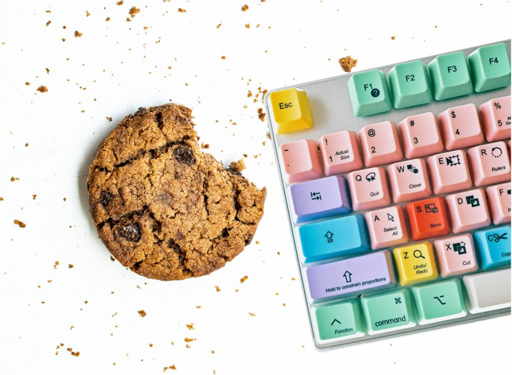 Ein Keks liegt neben einer Tastatur.
